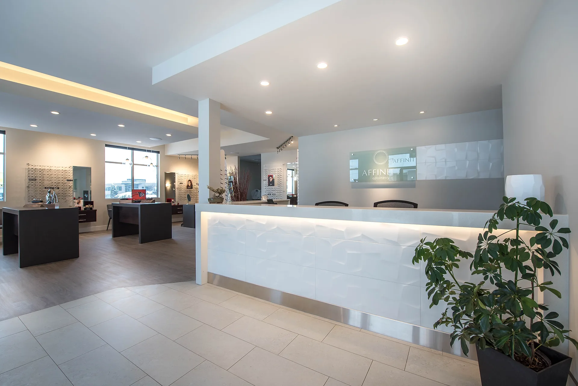 Affinity Optometry reception with a backlit curved feature desk, tile flooring, and a bright retail dispensary beyond