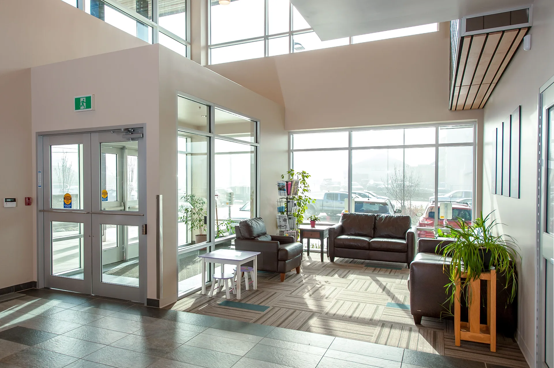 School District No. 83 Education Support Centre entry lobby with double-height glazing, clerestory daylight, and informal seating